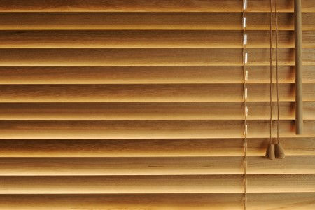 Closed wooden blinds with bright light coming through background